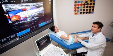 Doctor performing ultrasound examination on patient leg for neuromuscular assessment